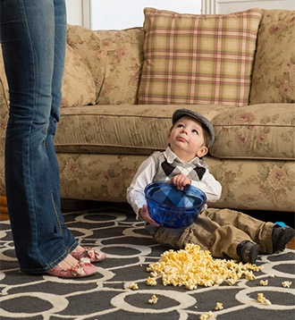 A little boy sitting and some Popcorn has been fallen down in Carpet