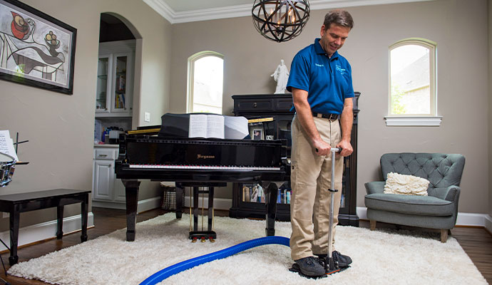 A professional of Dalworth Clean operating water extraction tool on rug
