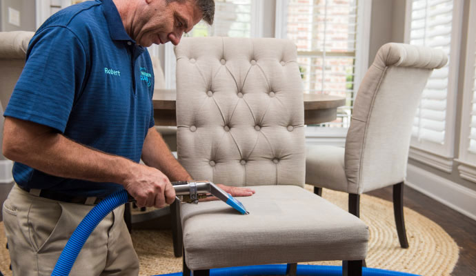 A technician is cleaning an upholstered chair.