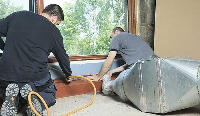 Person cleaning air duct with equipment