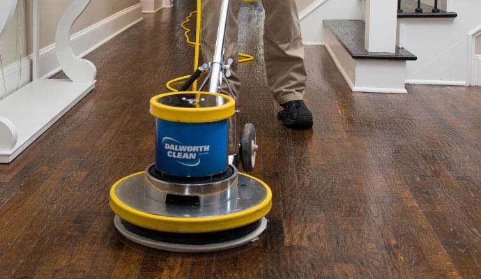 Dalworth Clean technician cleaning wood floors with a floor buffer machine