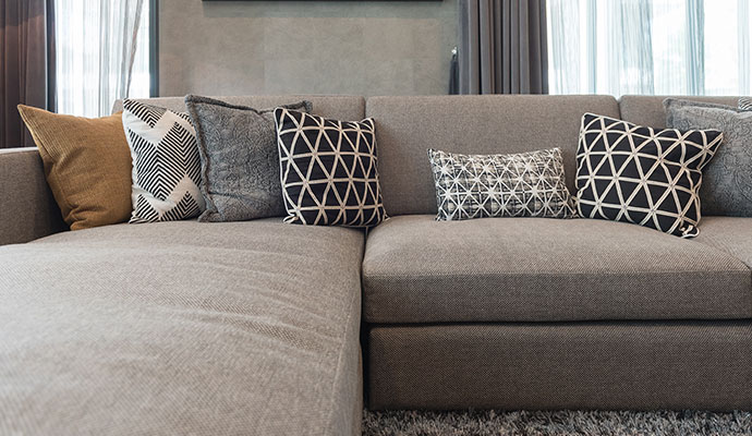Modern gray sectional sofa with patterned throw pillows arranged neatly in a living room
