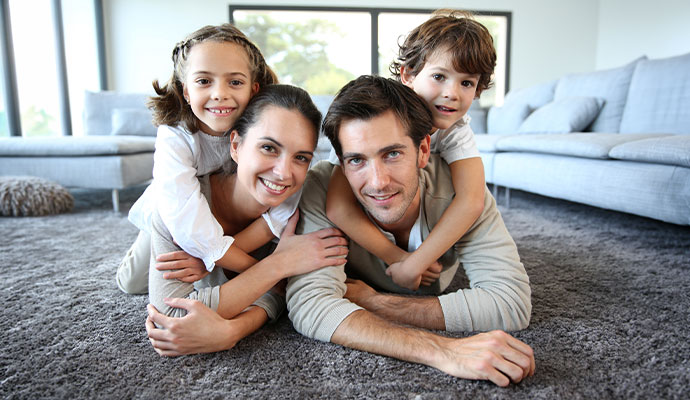 Parents and young kids lying together on carpeted floor