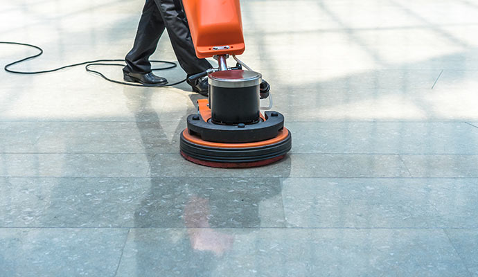 Worker is cleaning porcelain tile with-machine.