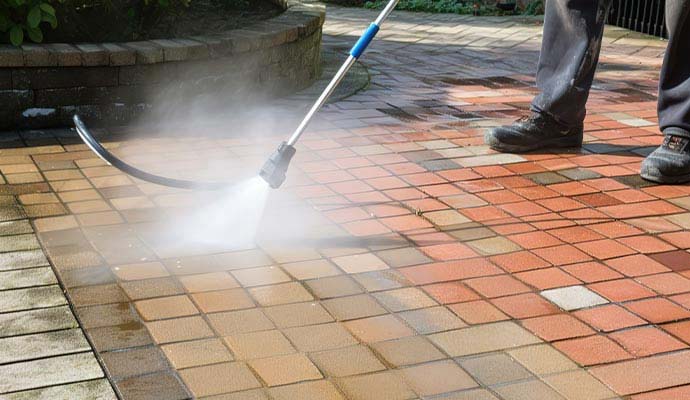 Pressure washing outdoor brick paver patio walkway