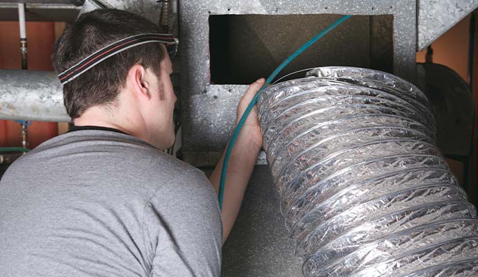 Technician cleaning and inspecting an air duct system