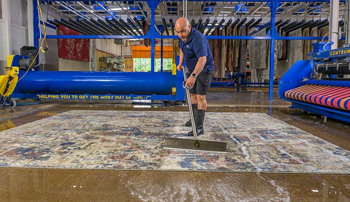 Technician cleaning and washing a large area rug