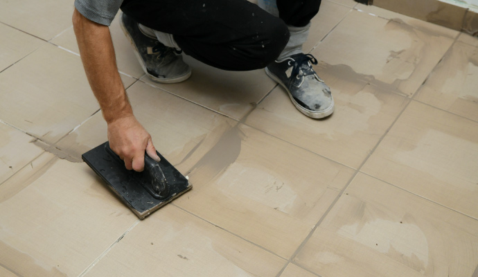 An expert applying grout sealing to a tile floor