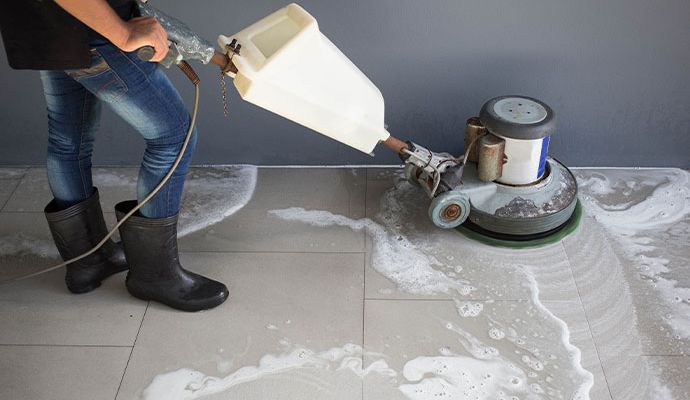Person cleaning tile floor with equipment