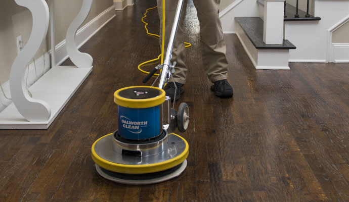 Technician cleaning wood floor with equipment