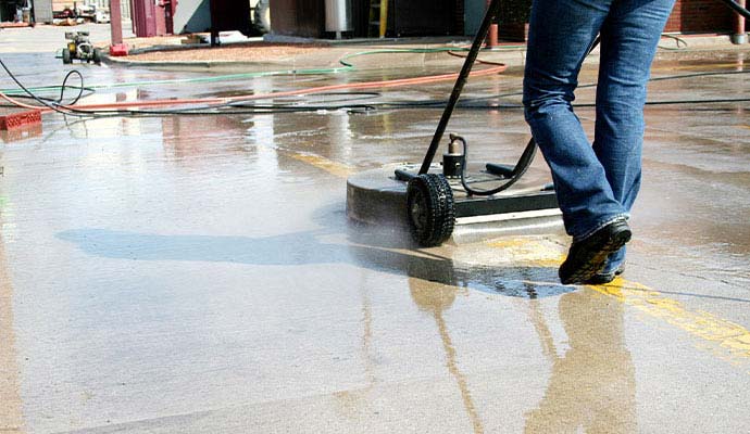 Worker using a surface cleaner tool for concrete cleaning